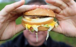 Government Backs TV Adverts To Promote Healthier Eating...BRISTOL, ENGLAND - JANUARY 07:  In this photo-illustration a man holds a burger from a fast food outlet on January 7, 2013 in Bristol, England.  A government-backed TV advert - made by Aardman, the creators of Wallace and Gromit - to promote healthy eating in England, is to be shown for the first time later today. England has one of the highest rates of obesity in Europe - costing the NHS 5 billion GDP each year - with currently over 60 percent of adults and a third of 10 and 11 year olds thought to be overweight or obese.  (Photo by Matt Cardy/Getty Images)