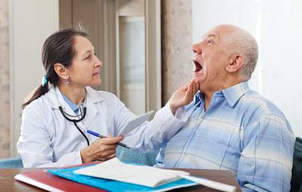 Female mature doctor looks the mouth of senior patient in clinic